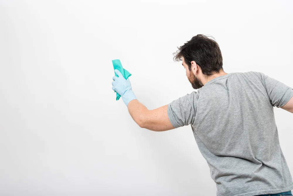 Como tirar gancho adesivo da parede 3 concept man cleaning his home with copyspace wall